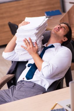 Ofisteki aşırı işten memnun olmayan genç bir erkek işçi.