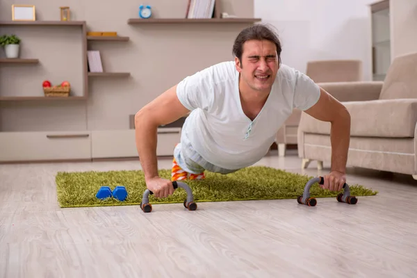 Jovem fazendo exercícios esportivos em casa — Fotografia de Stock