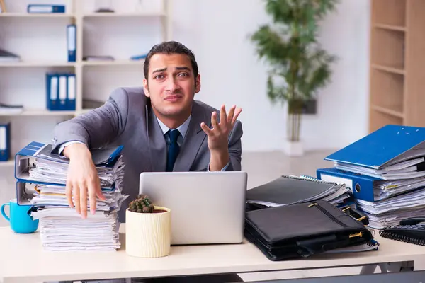 Joven empleado masculino infeliz con el trabajo excesivo — Foto de Stock