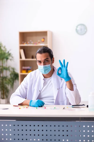 Joven químico masculino trabajando en el laboratorio durante una pandemia — Foto de Stock