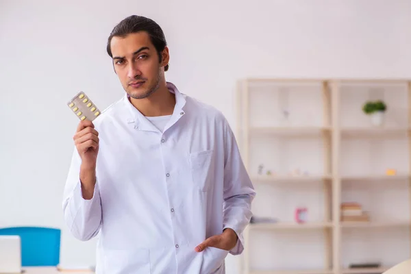 Joven médico masculino sugiriendo pastillas en la clínica — Foto de Stock