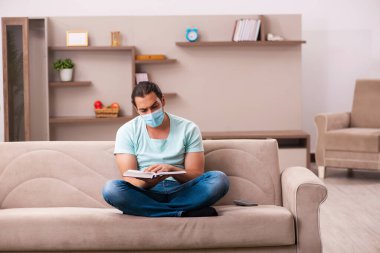 Genç erkek öğrenci salgın sırasında evde çalışıyor.