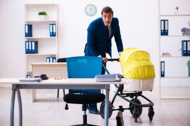 Genç erkek çalışan işyerinde çocuğa bakıyor.