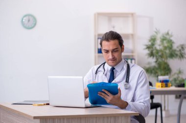 Genç erkek doktor hastanede not alıyor.