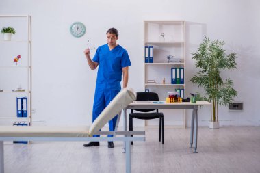 Klinikte çalışan genç erkek doktor.