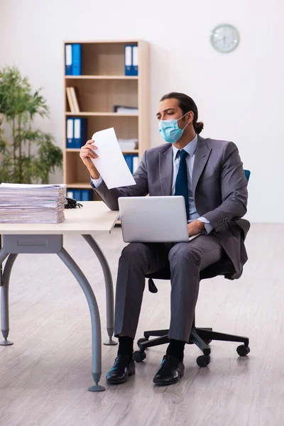 Jovem funcionário do sexo masculino usando máscara durante pandemia — Fotografia de Stock