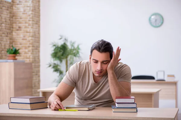 Jonge mannelijke student bereidt examens in de bibliotheek voor — Stockfoto