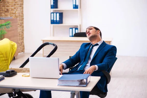 Ung manlig anställd som tar hand om barn på arbetsplatsen — Stockfoto