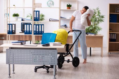 İş yerinde yeni doğan bebeğe bakan genç bir erkek işçi.