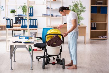 İş yerinde yeni doğan bebeğe bakan genç bir erkek işçi.