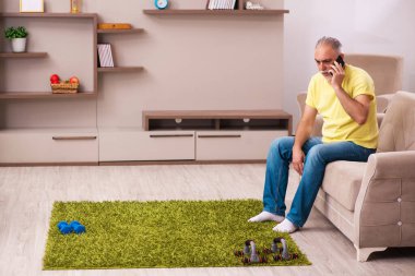 Yaşlı adam evde spor egzersizleri yapıyor.