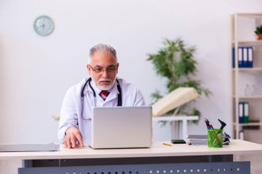 Klinikte çalışan yaşlı erkek doktor.