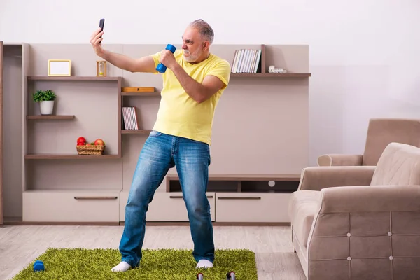 У віці чоловік робить спортивні вправи вдома — стокове фото