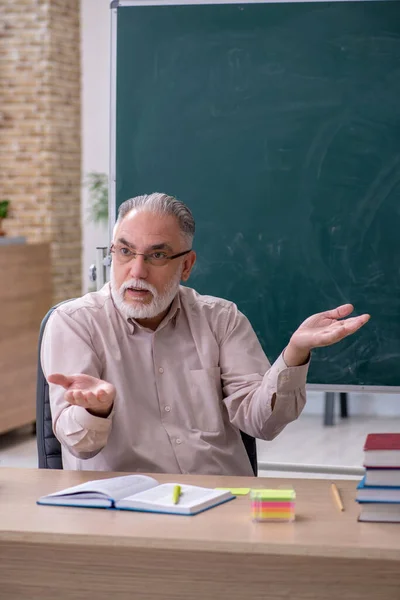 Old male teacher sitting in the classroom — Stock Photo, Image