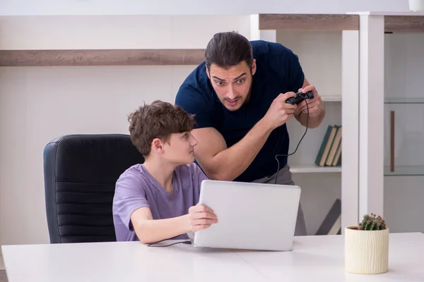 Mladý otec a školák hrají počítačové hry doma — Stock fotografie