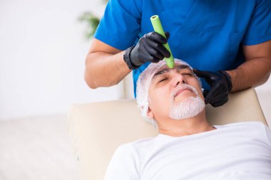 Yaşlı adam estetik ameliyat için erkek doktoru ziyaret ediyor.