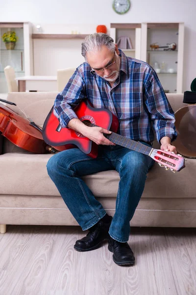 Hombre mayor reparador reparando instrumentos musicales en casa — Foto de Stock