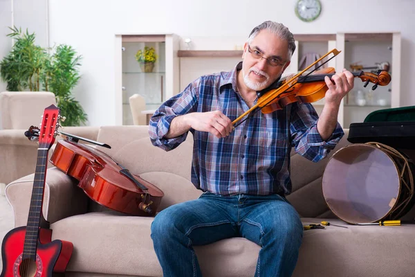 Hombre mayor reparador reparando instrumentos musicales en casa —  Fotos de Stock