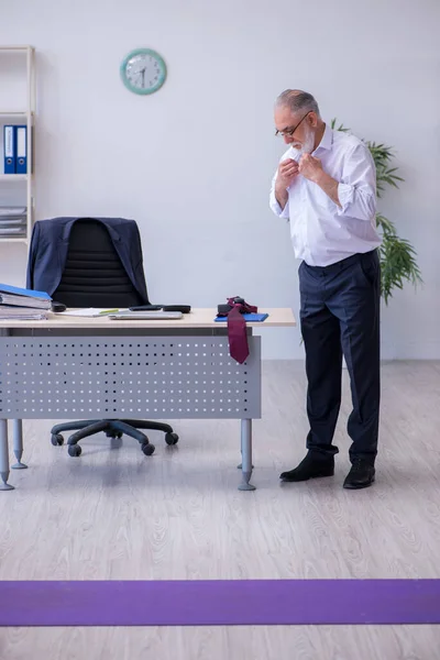 Aged male employee doing physical exercises during break — Stock Photo, Image