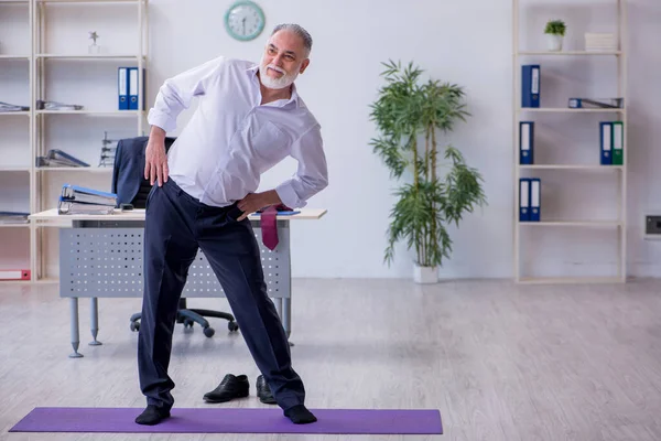 Ältere männliche Mitarbeiter machen in der Pause körperliche Übungen — Stockfoto