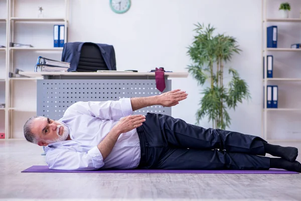 Мужчина в возрасте делает физические упражнения во время перерыва — стоковое фото