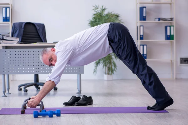 Ältere männliche Mitarbeiter machen in der Pause körperliche Übungen — Stockfoto