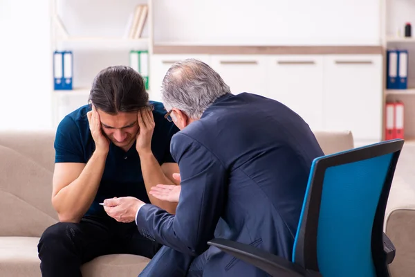 Young man visiting old male psychologist — Stock Photo, Image