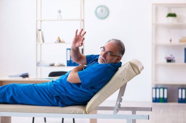 Yaşlı erkek doktor gece vardiyasından sonra çok yorgun.