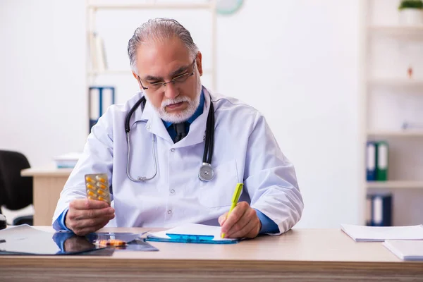 Alte männliche Arzt schreibt Rezept in der Klinik — Stockfoto