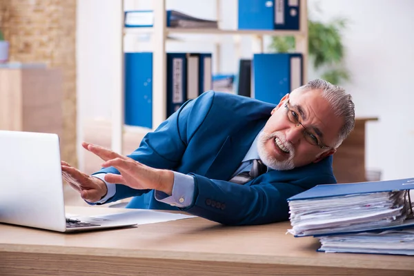 Oude mannelijke boekhouder ongelukkig met buitensporig werk op de werkplek — Stockfoto