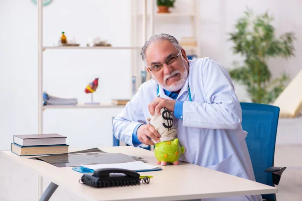 Alte männliche Arzt hält Geldbeutel im Krankenhaus — Stockfoto