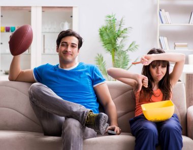 Adam karısıyla Amerikan futbolu seyrediyor.