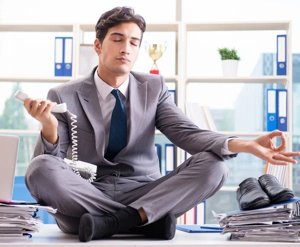 Businessman sitting on top of desk in office — Stock Photo, Image