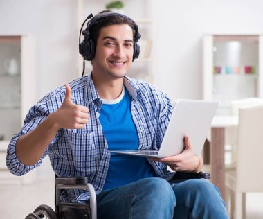 Tekerlekli sandalyede müzik dinleyen engelli adam.