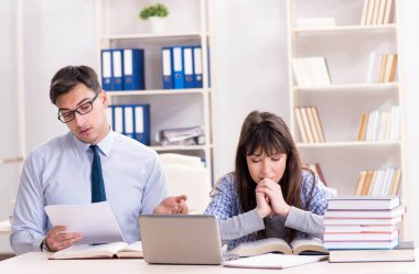 Erkek öğretim görevlisi bayan öğrenciye ders veriyor.