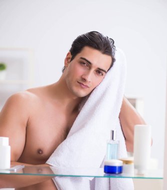 Genç adam banyoda çalışmak için hazırlanıyor.