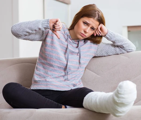 Jeune femme avec jambe cassée à la maison — Photo