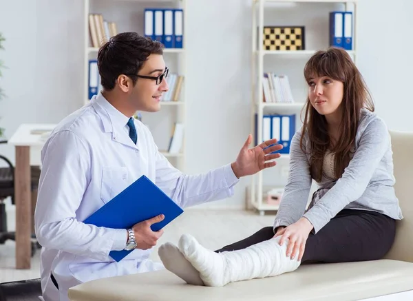 Médecin examinant patient avec jambe cassée — Photo