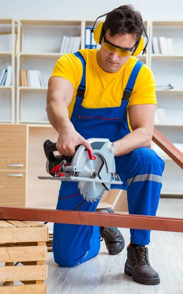 Reparador carpintero cortando aserrar una tabla de madera con un circuito — Foto de Stock