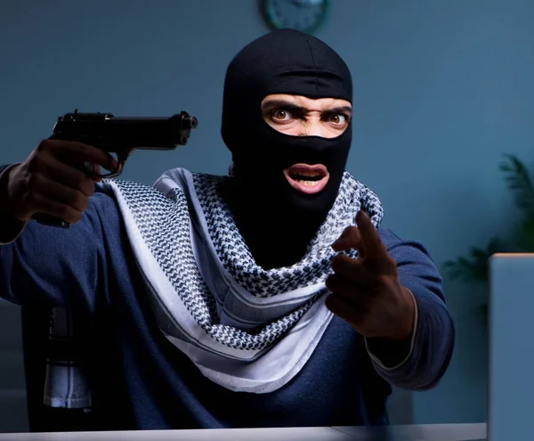 Teroristický lupič se zbraní pracující v počítači — Stock fotografie