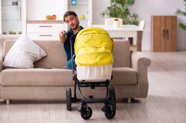 Genç baba yeni doğan bebeğe bakıyor.