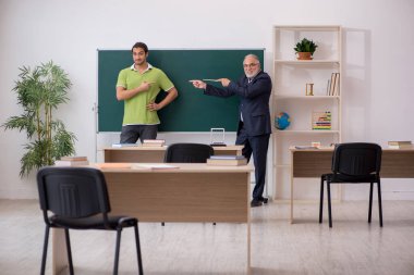 Sınıfta yaşlı öğretmen ve erkek öğrenci var.