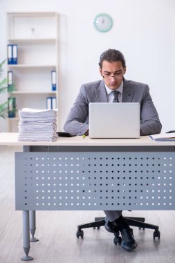 Ofisteki aşırı işten memnun olmayan genç bir erkek işçi.