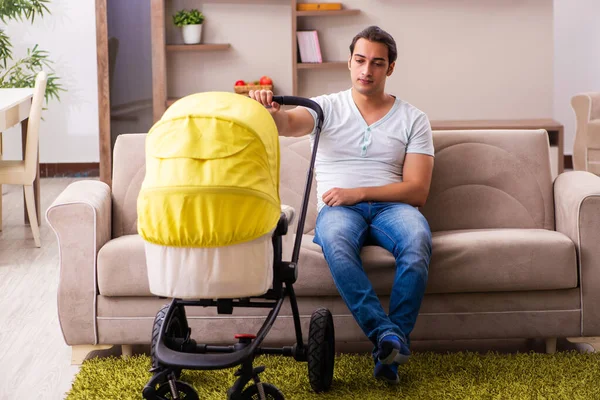 Jovem empreiteiro masculino cuidando de recém-nascido em casa — Fotografia de Stock
