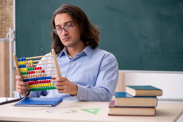 Young male teacher in front of green board