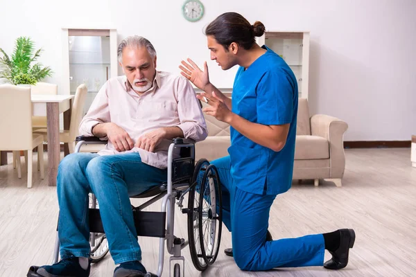 Oude man in rolstoel en jonge slechte verzorger binnen — Stockfoto