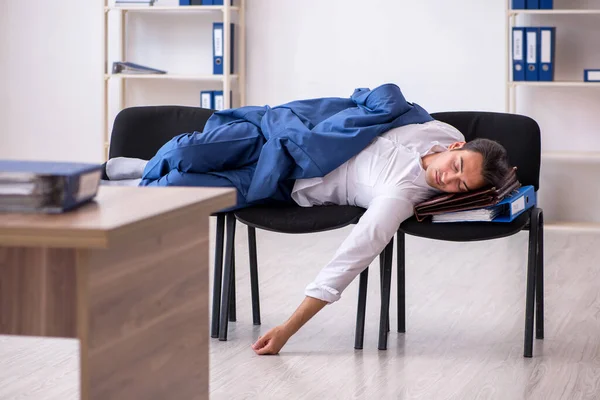 Молодой работник спит в офисе на стульях — стоковое фото