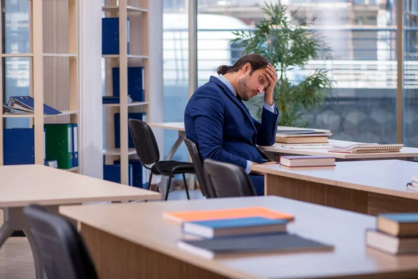 Sınıfta takım elbiseli genç bir erkek öğretmen var.