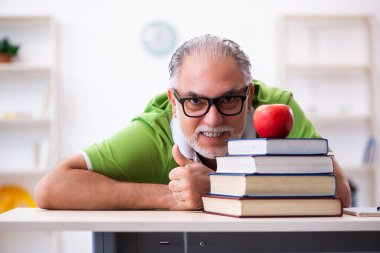 Sınav hazırlıkları sırasında elma yiyen yaşlı bir erkek öğrenci