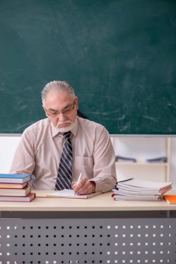 Sınıftaki yaşlı erkek öğretmen.